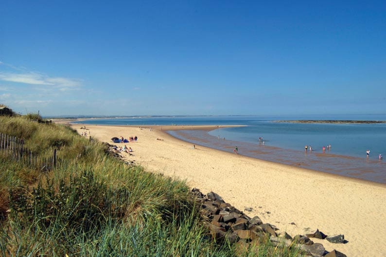 Grassy dunes behind a sandy beach at Cresswell Bay in Northumberland