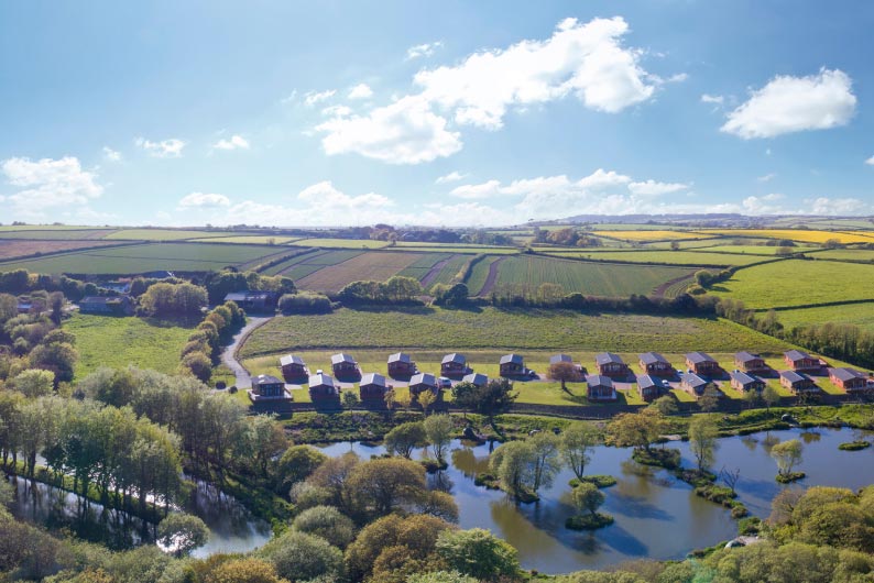 Lodges overlooking a fishing lake at White Acres Holiday Park in the Cornish countryside