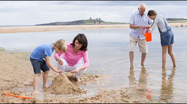 Grandparents playing in sand with grandchildren