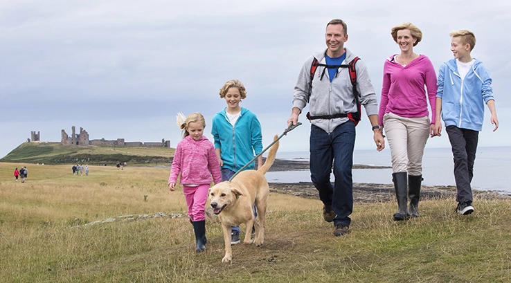 Family Walking Along Clifftop with Dog