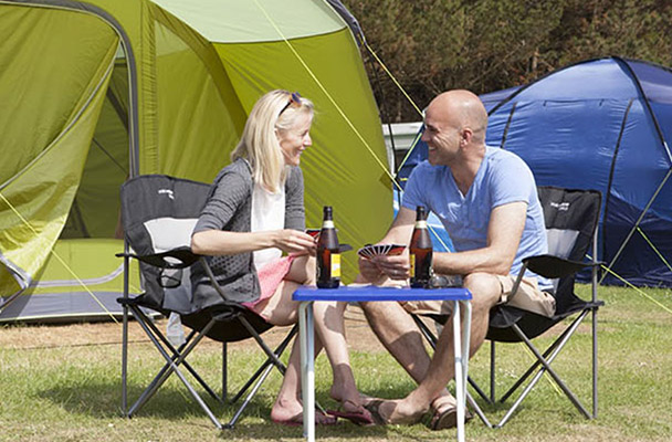 A couple enjoying beers outside their tent