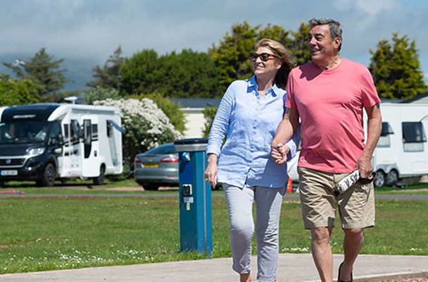 A couple walking through the touring area of a holiday park
