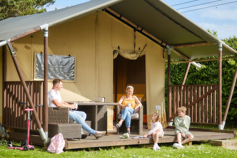 Glamping pod with family sat outside in the sunshine