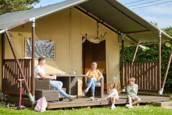 Glamping pod with family sat outside in the sunshine