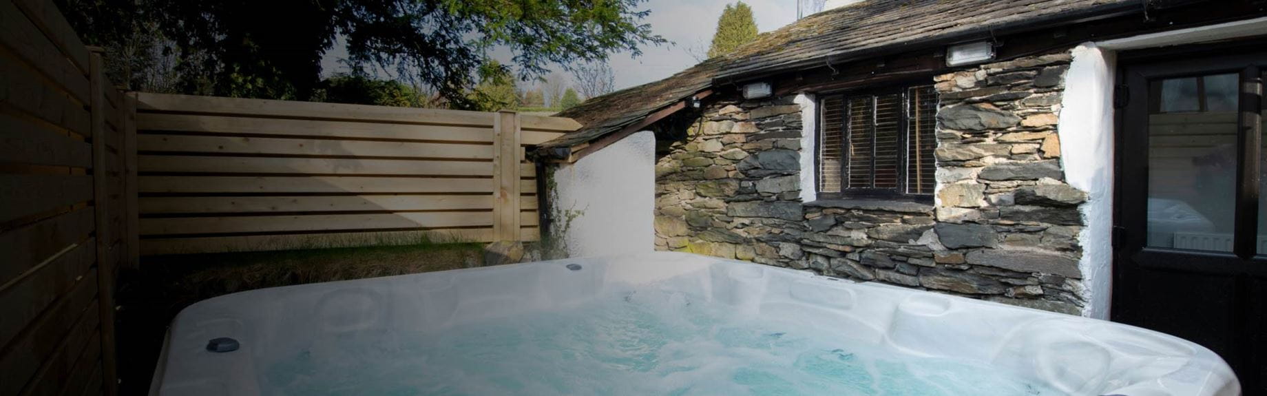 A hot tub outside of a stone bungalow 