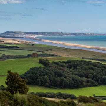 A view of countryside and a long stretch of beach in a sweeping bay on the UK's coastline