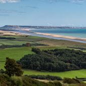 A view of countryside and a long stretch of beach in a sweeping bay on the UK's coastline