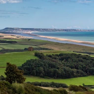A view of countryside and a long stretch of beach in a sweeping bay on the UK's coastline