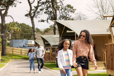 A family walking past a row of glamping tents at Newquay Holiday Park