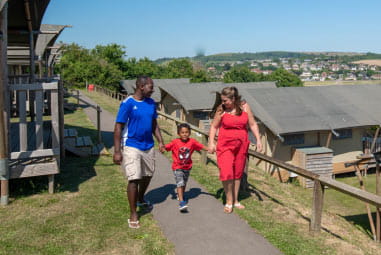 People walking past rows of glamping tents at West Bay Holiday Park