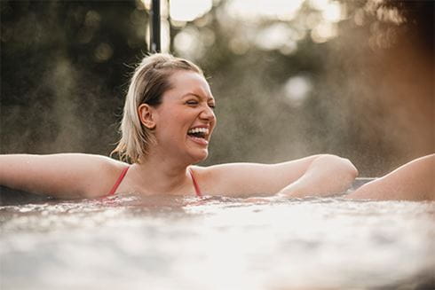 A woman laughing with friends while relaxing in a hot tub at a Parkdean Resorts lodge