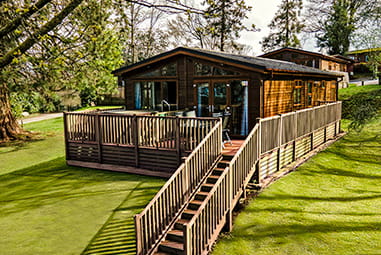 The exterior of a hot tub lodge at Parkdean Resorts showing the decking and outdoor sitting area