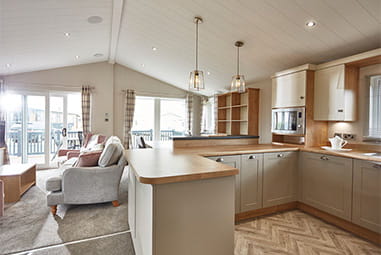 An interior of a stylish hot tub lodge at Parkdean Resorts, showing the open plan kitchen, breakfast bar and living room