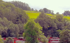 Holdiay lodges nestled amongst the trees in a countryside valley