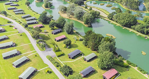 Lodges around a fishing lake at White Acres Holiday Park in Cornwall