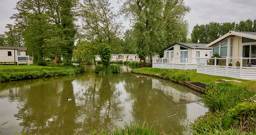 Lodges overlooking a pond at Weeley Bridge Holiday Park in Essex