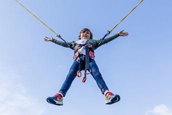 A boy jumping in the air on a bungee trampoline