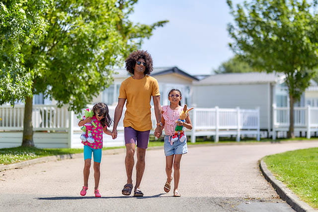 A family walking through a sunny holiday park setting