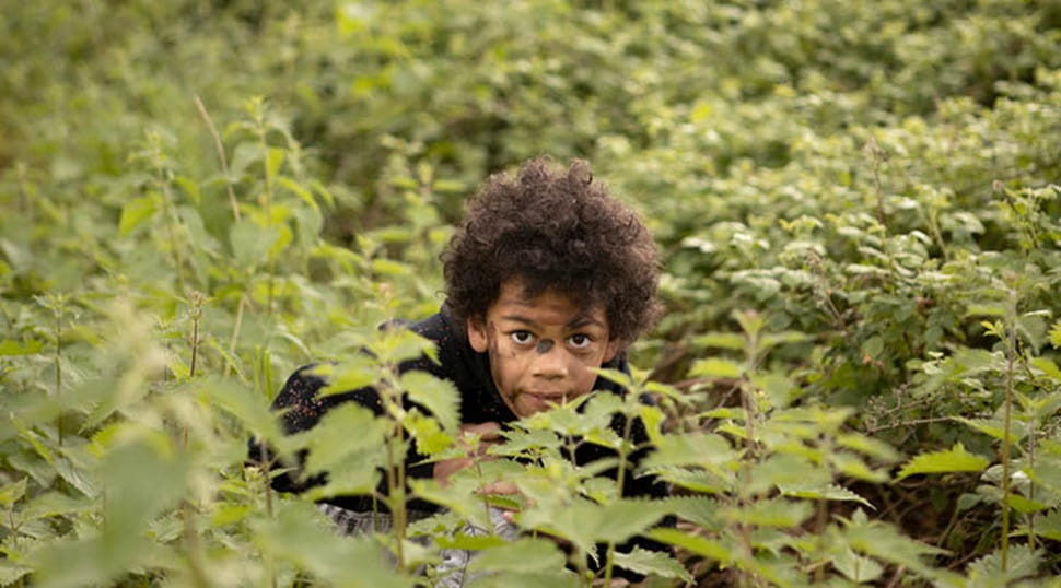 A boy hiding in the bushes