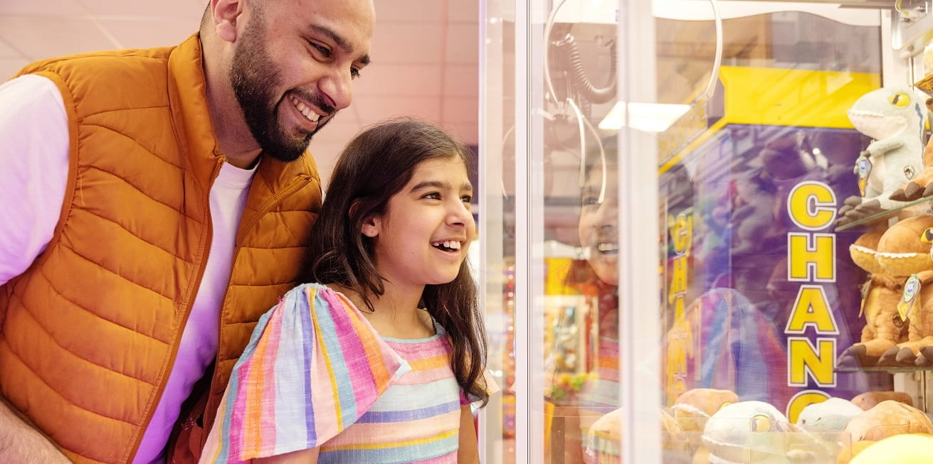 father and daughter playing an amusement arcade game
