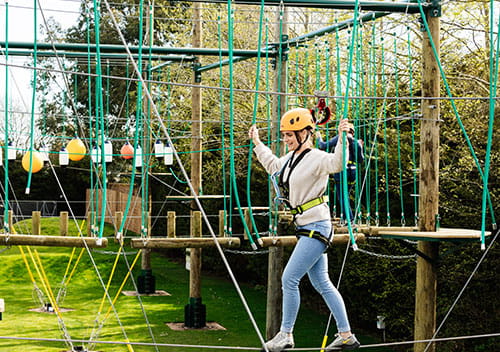 Girl wearing yellow hat and harness on the high ropes
