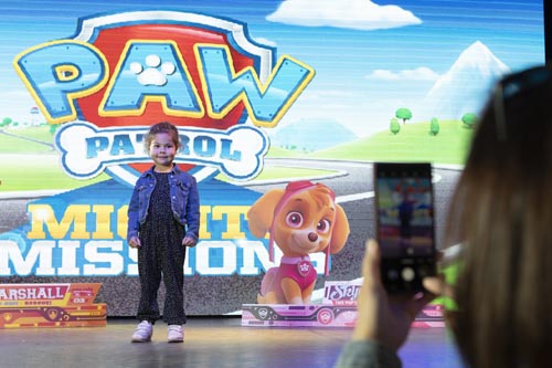 Little girl stood on stage with mum taking a photo