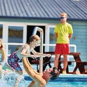 A lifeguard overseeing people in an outdoor swimming pool
