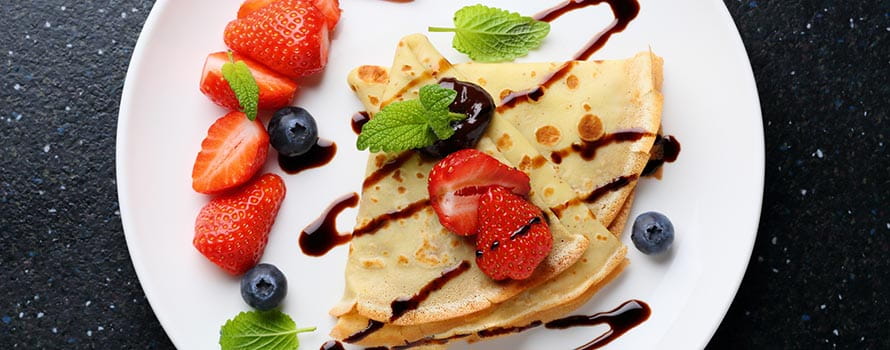 Crepes with fruit and icing sugar