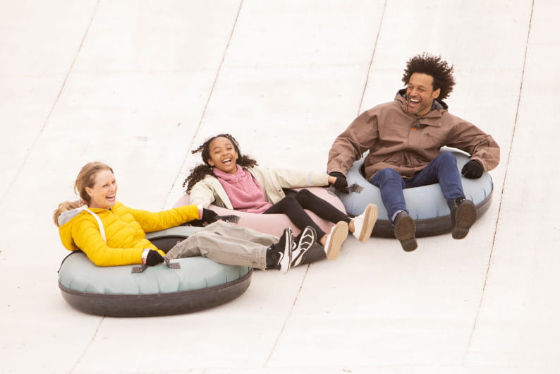 Family tubing down a ski slope