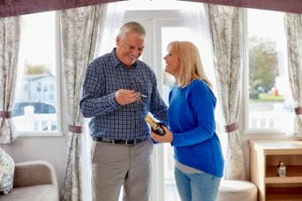 Couple smiling with keys to their new caravan