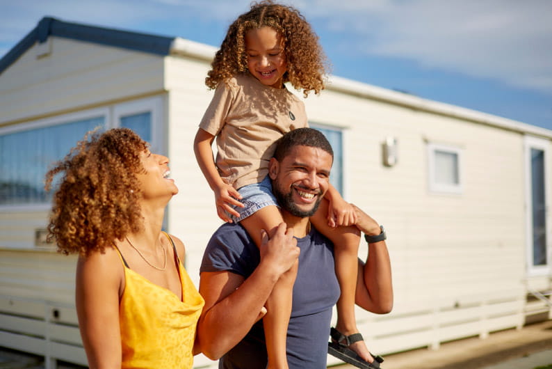 Family smiling with child on shoulders