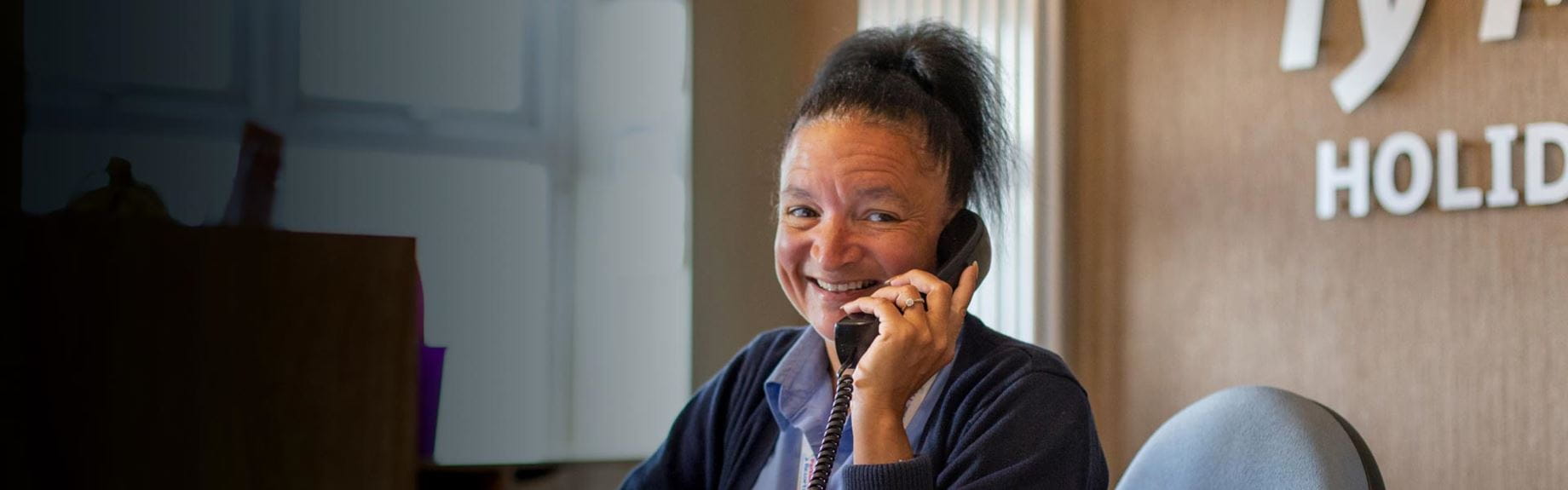 Receptionist smiling at the camera on the phone at Parkdean Resorts