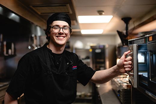 Happy chef employee at work in the kitchen