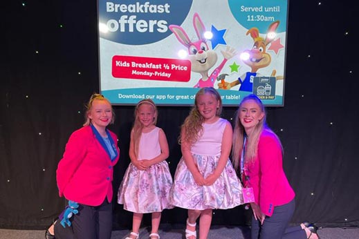 Little girls smiling on stage with Parkdean Resorts staff