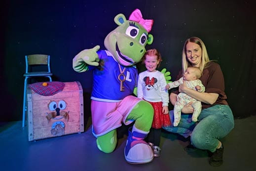 Family smiling on stage with character dressed up in fancy dress