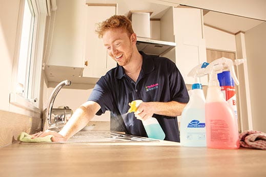 Holiday park employee cleaning caravan