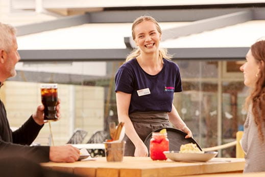 Young female waitress serving food and drinks