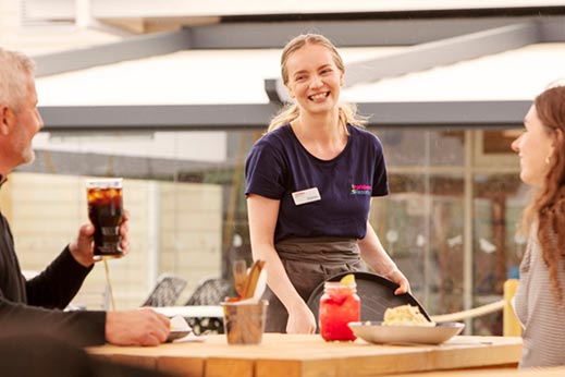 Young female waitress serving food and drinks