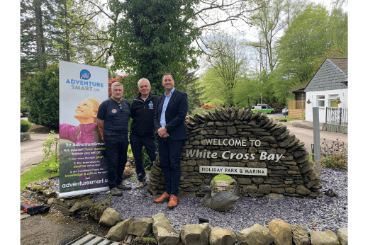 A group of three men stood in front of a holiday park sign