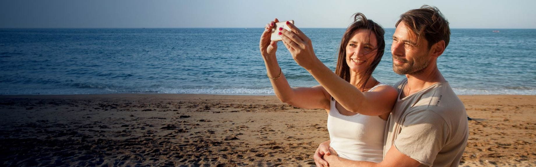 Couple stood on beach taking a selfie