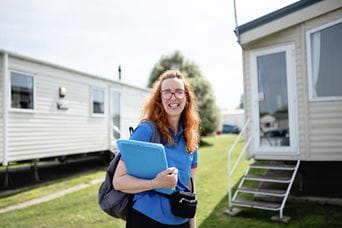 Girl with red curly hair wearing a blue top holding a clip board