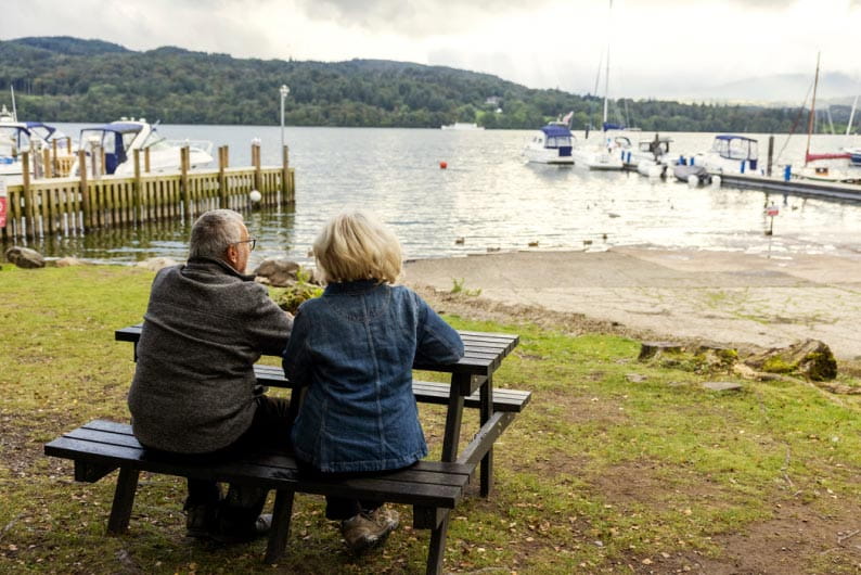 Couple sat at picnic bench looking out onto the lake