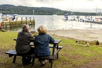 Couple sat at picnic bench looking out onto the lake
