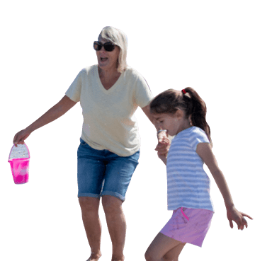 Mum and daughter holding hands on a beach holding a pink bucket