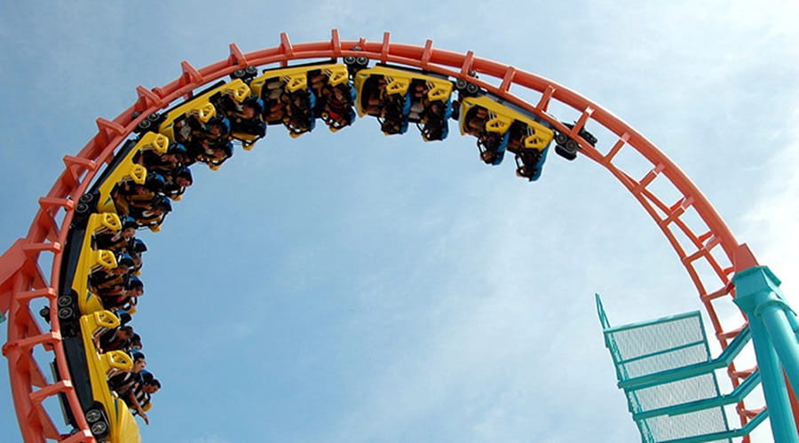 People riding a roller coaster as it loops upside down