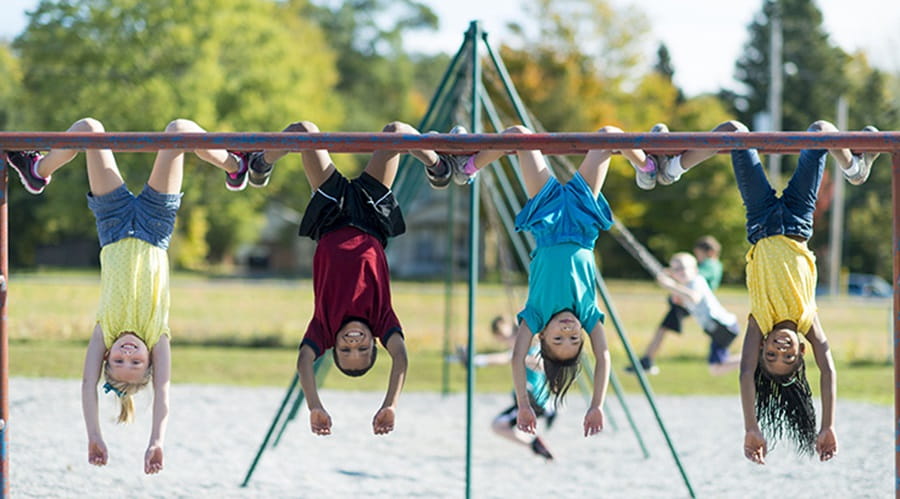 Children hanging upside down on climbing frame
