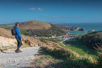 A woman hiking down the hill towards Lulworth Cove in Dorset, near Warmwell
