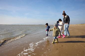 A family walking along a sandy beach in autumn