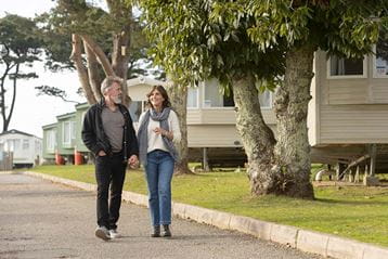A couple strolling through Looe Bay Holiday Park in Cornwall