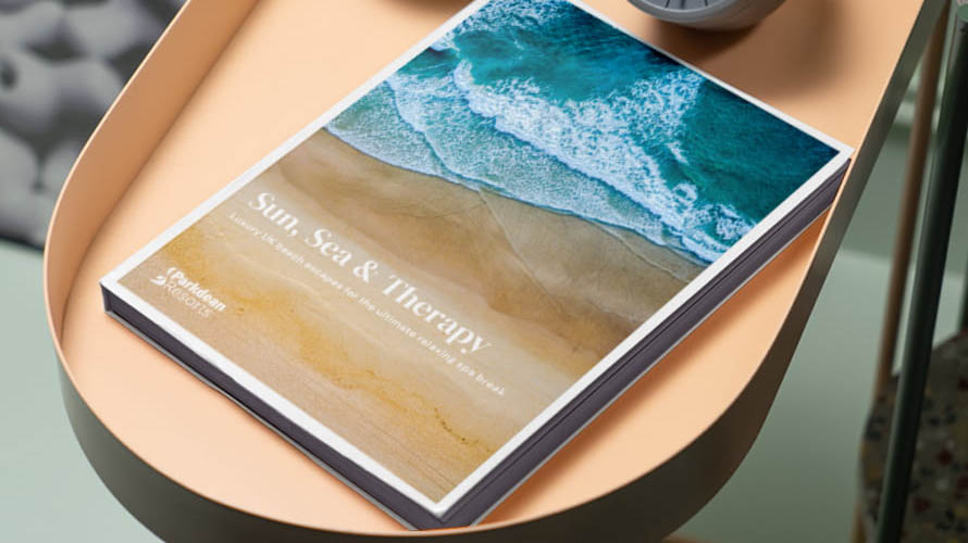 A Parkdean Resorts brochure on a side table showing a picture of a beach